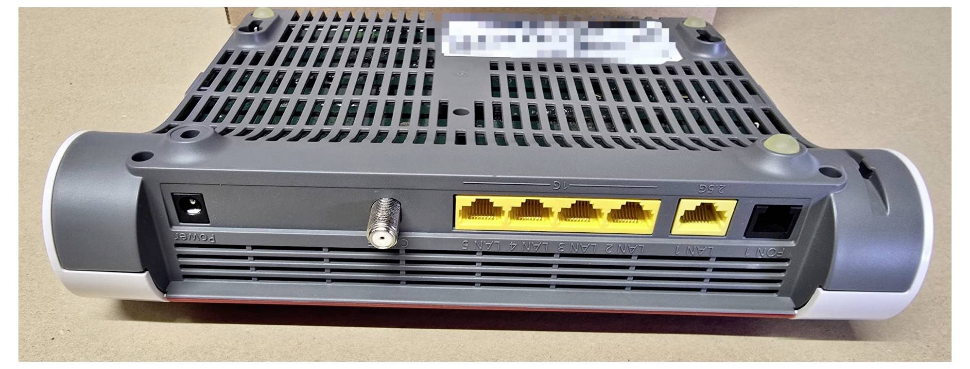 'Back view of a router showing four yellow Ethernet ports, a coaxial cable input, and power connection on a beige surface.'