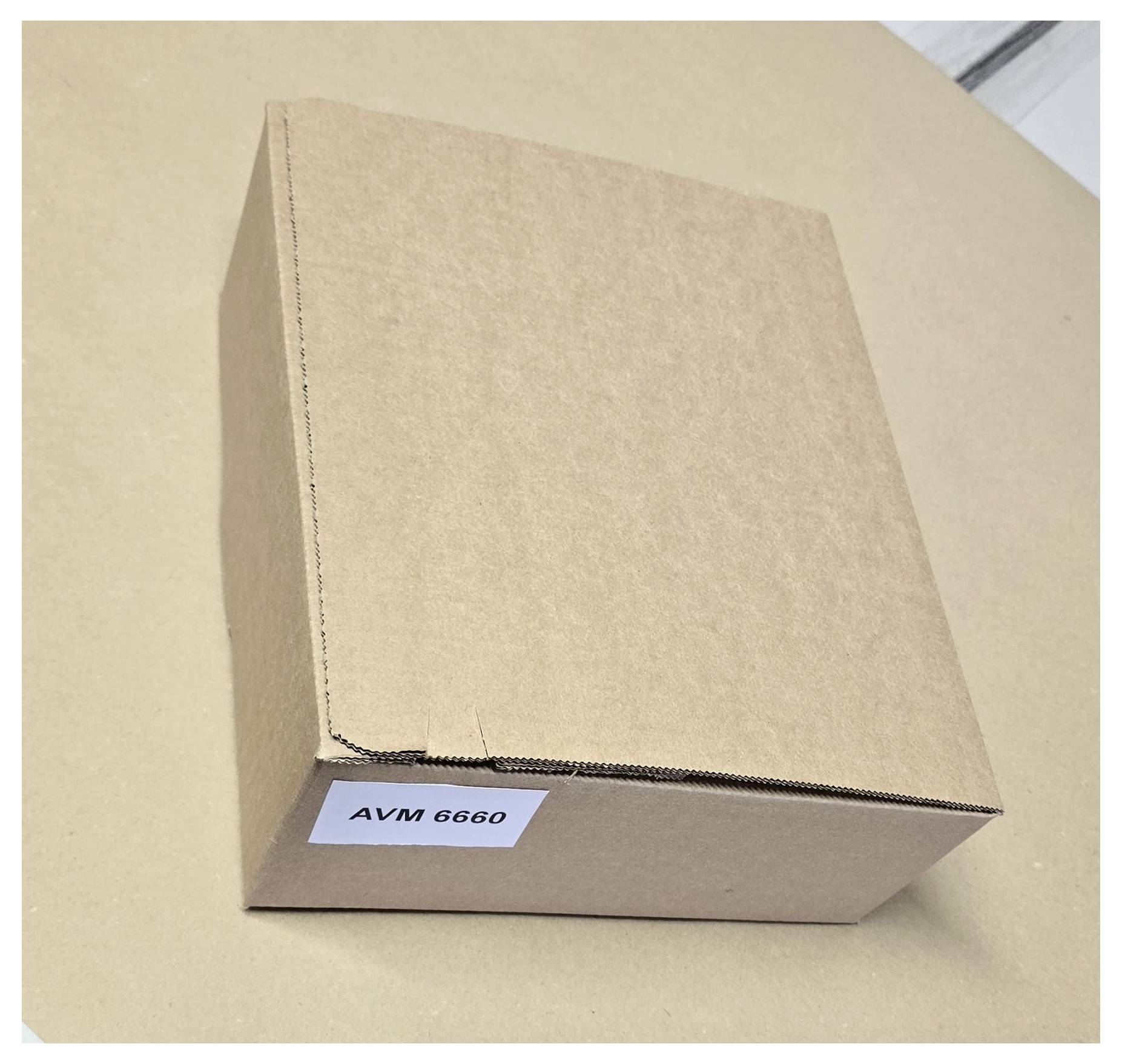 A closed cardboard box labeled 'AVM 6660' on a flat surface.