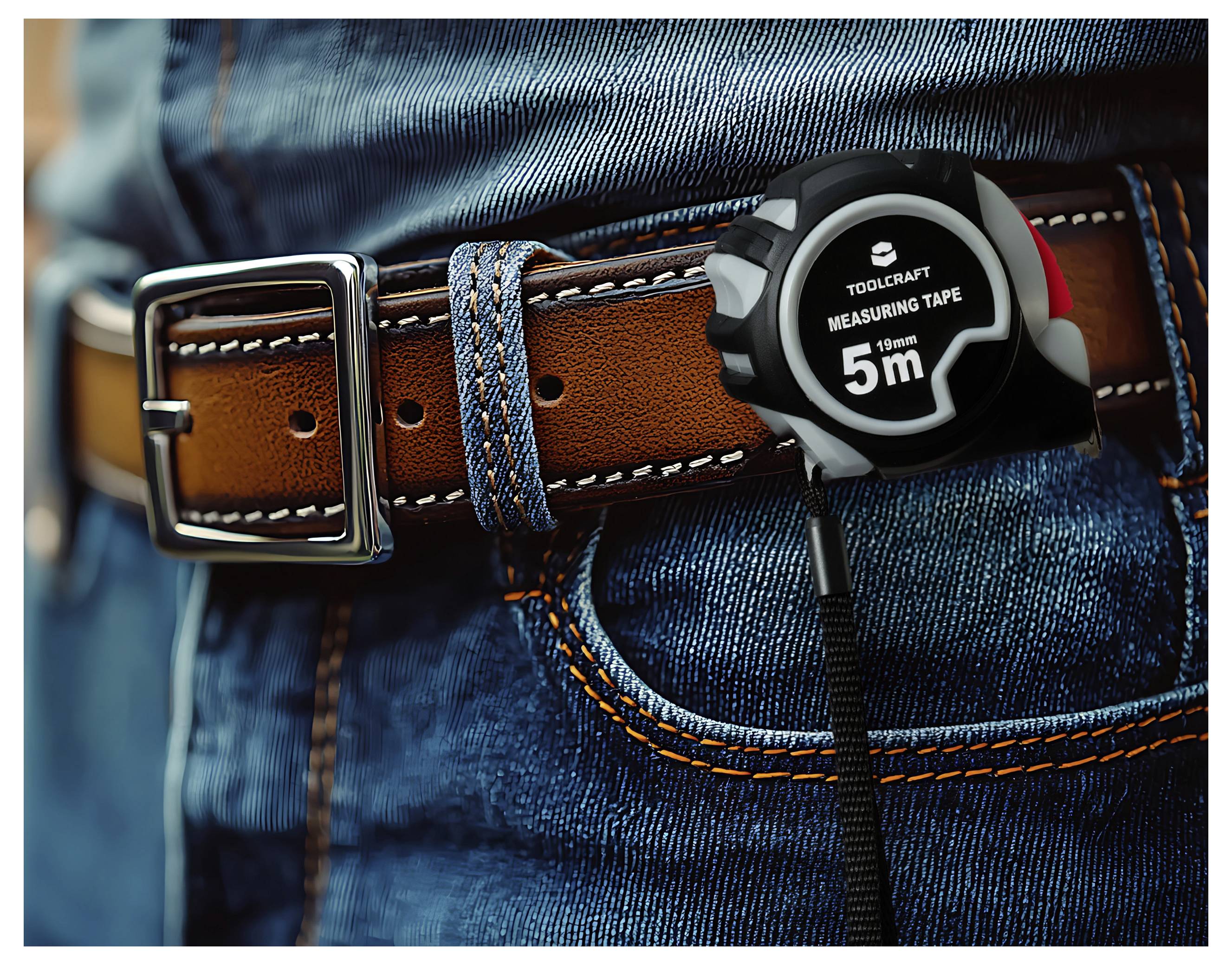 Close-up of a person wearing blue jeans and a brown leather belt with a 5m measuring tape clipped to it.