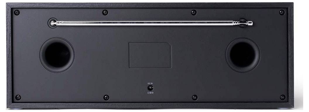 The image shows the back of a black soundbar speaker with a metal handle and two ports, designed for audio output.