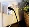 White wall outlet with a plug adapter and two cords connected beside a potted plant, suggesting a powered charging setup.