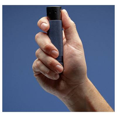A person holds a small cylindrical device with a textured grip, against a plain blue background, suggesting utility or tech use.