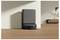 'Robotic vacuum in a modern living room, docked in a charging station against a beige wall, wooden floor, and minimalist furniture.'