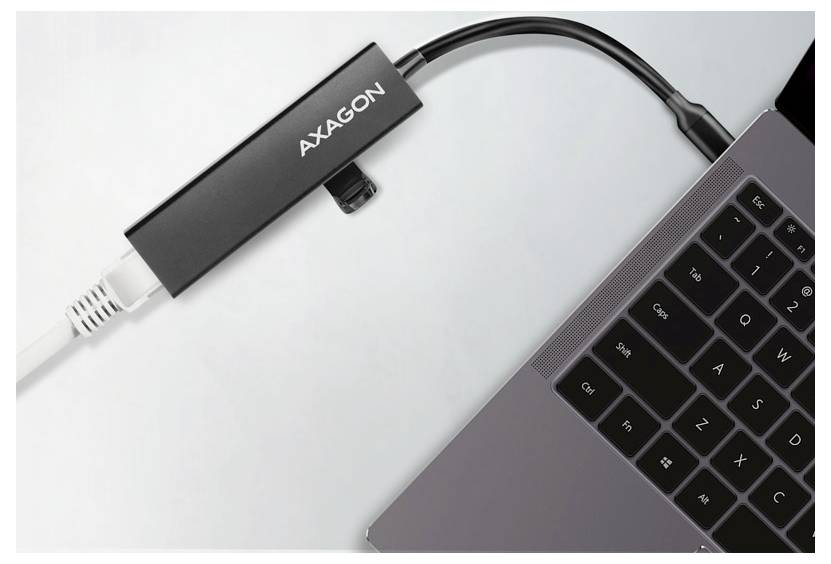 AXAGON USB-C adapter connected to a laptop, with a white cable plugged into the adapter and a black cable running to the computer.<br>