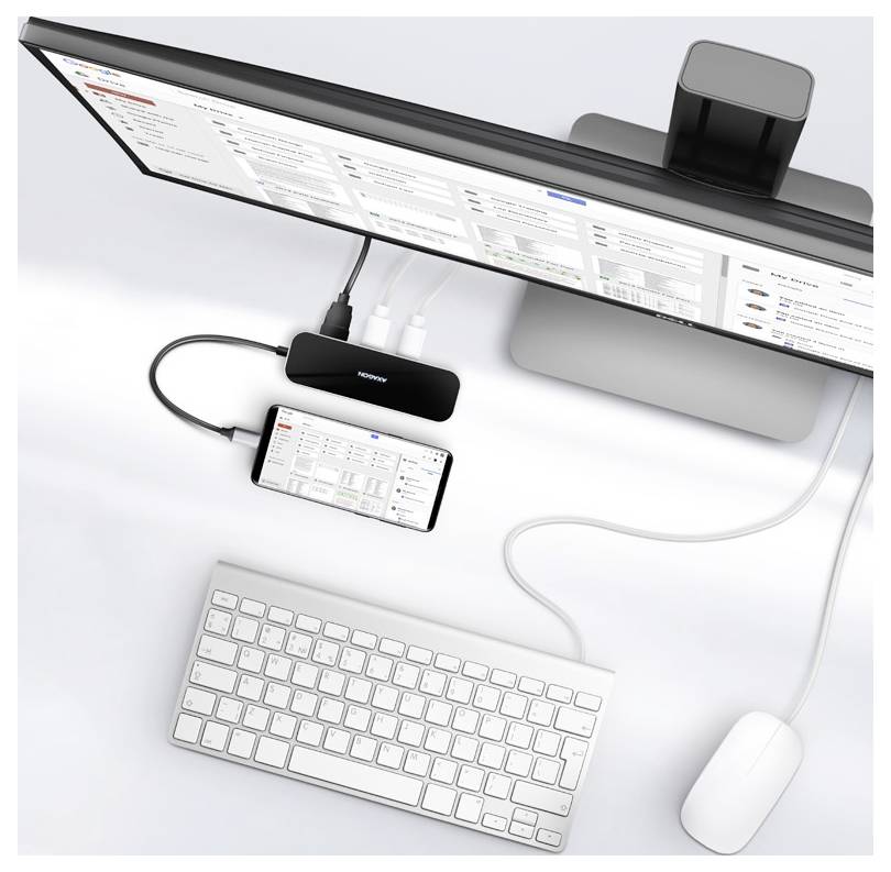 Top-down view of a desktop setup with an ultrawide monitor, docked smartphone, keyboard, mouse, and a small hub connected by cables.<br>