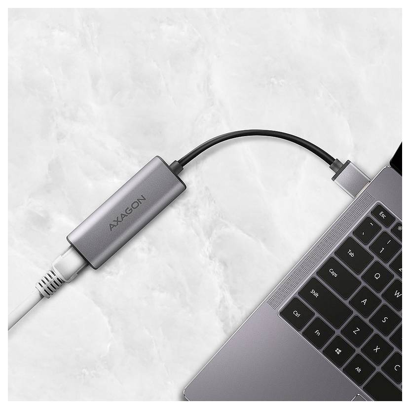 USB-C adapter cable connecting an AXAGON dongle to a laptop on a light surface.