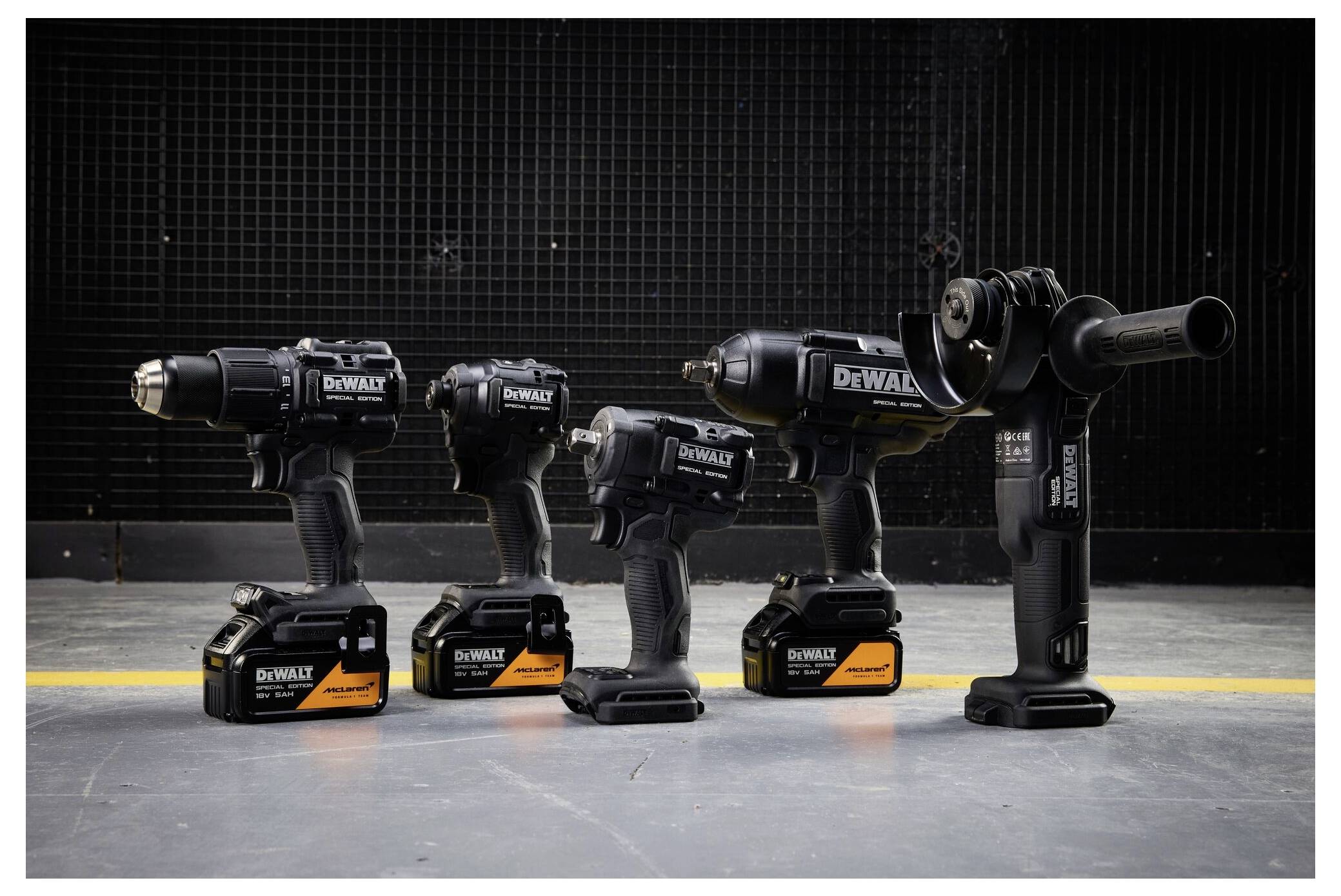 Four DeWalt cordless power tools on a concrete floor: three drill/drivers and one compact tool, with a right-side drill fitted with an attachment.