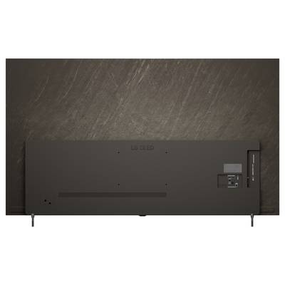 Back view of a flat-screen LG OLED TV mounted on a wall, showing ports, stand legs, and cable connections.