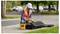 Utility worker in hard hat and safety vest operating roadside testing equipment beside an open case near the curb.