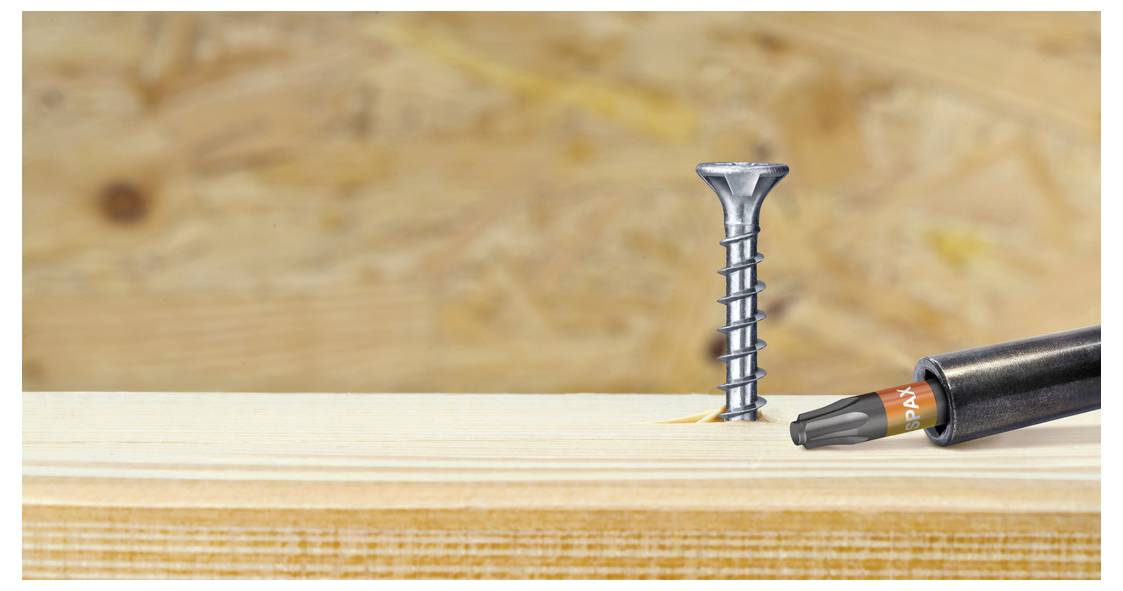 A screw being driven into a wooden board with a power drill, showing close-up carpentry work.