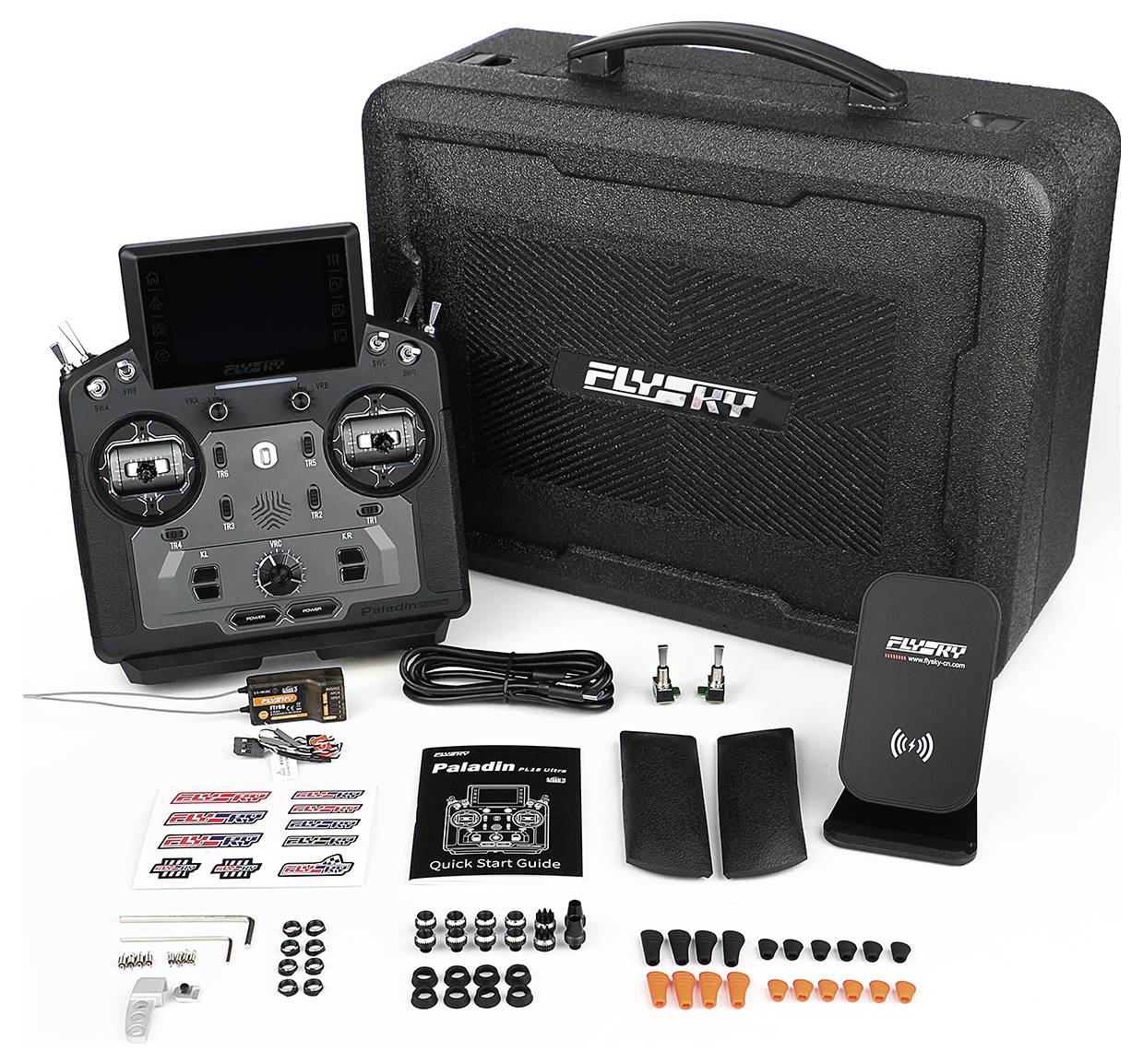 FlySky remote-control transmitter kit with case, receiver, cables, antennas, quick start guide, stickers, and spare parts laid out on a white background.