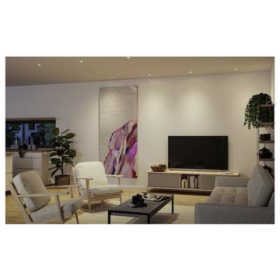 Modern living room with two chairs, sofa, coffee table, TV console, wall art, and warm recessed lighting.