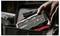 Hand places a NOCO Boost HD portable jump starter into an open carrying case.