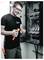Technician in a server or electrical cabinet inspects and handles wiring tools inside an open control panel.<br>