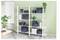 White shelving unit with gray storage boxes, books, and plants against a pale green wall in a bright room<br>