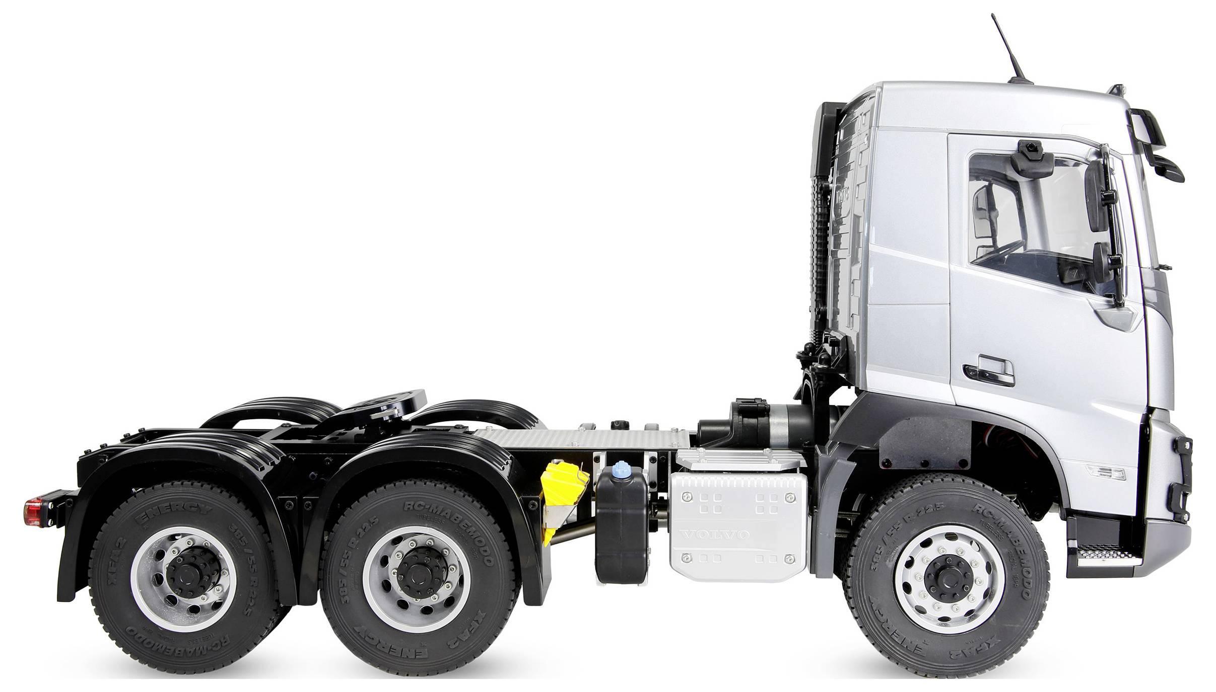 Side view of a white semi-truck chassis cab with no trailer, showing the cab, fuel tank, and multiple rear axles on a white background.