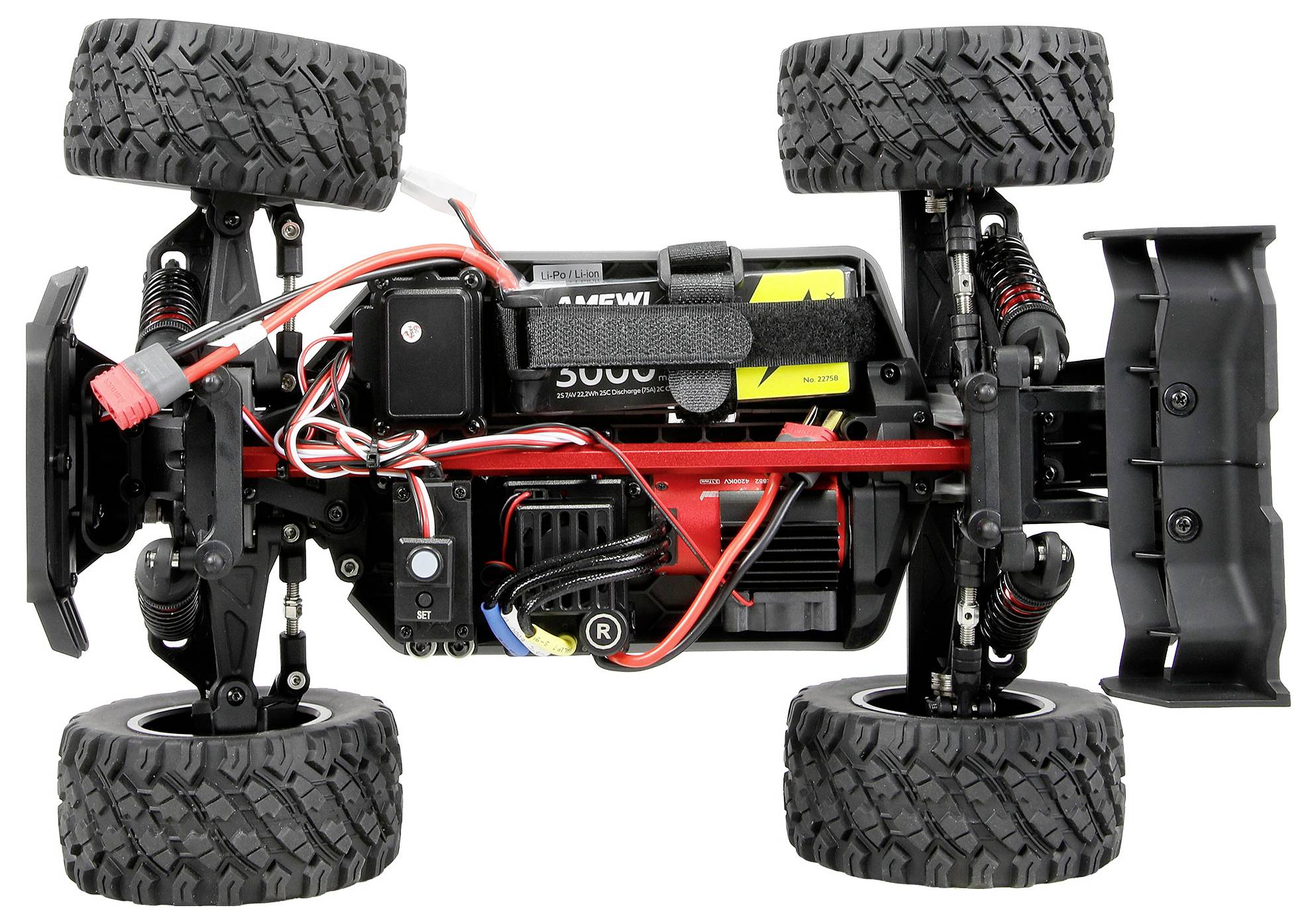 Upside-down RC truck chassis with four large off-road tires, exposed suspension, wiring, battery, and motor on a white background.