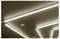 Ceiling with bright fluorescent light strips and recessed circular fixtures forming geometric lines on a brown surface.<br>