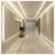 Modern minimalist hallway with glossy marble floor, recessed ceiling lights, beige walls, a potted plant on a small stand, and a door at the end.