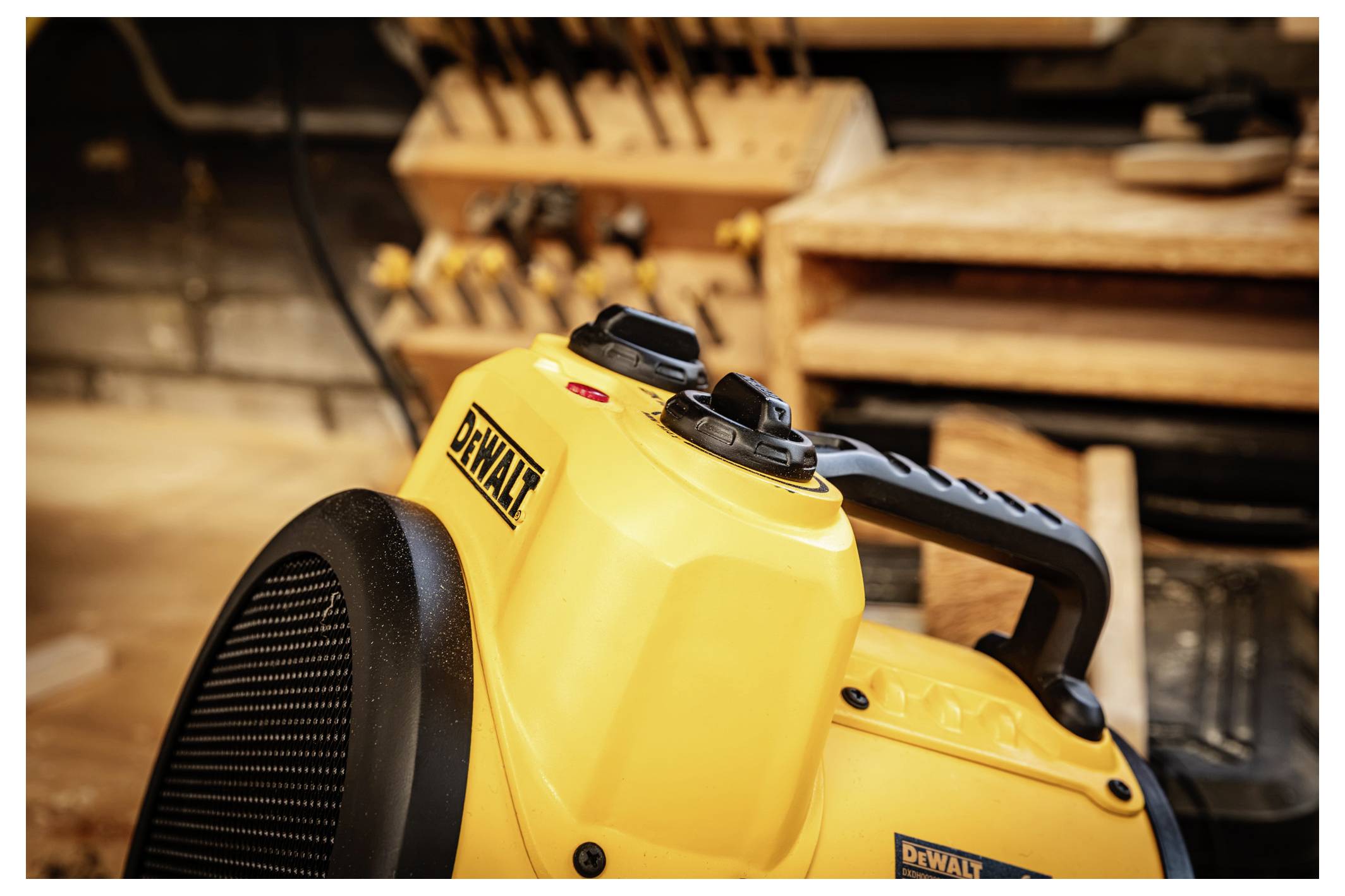 Yellow DeWalt portable fan/heater in a workshop, with tool shelves blurred in the background.