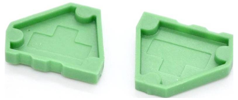Two green plastic puzzle-like pieces, each with an inset house-shaped outline and notched edges, shown side by side on a white background.