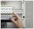 Hand turning off a Schneider Electric circuit breaker inside an electrical panel.<br>