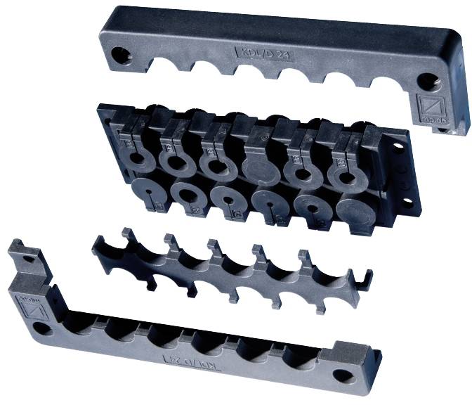 Exploded view of a black plastic cable clamp assembly with four interlocking parts, shown separated to illustrate how the pieces fit together.