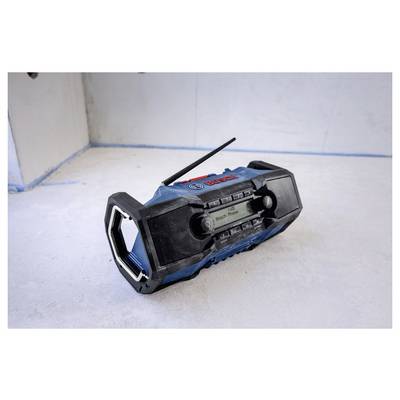 A blue and black Bosch portable radio sits on a white surface against a plain wall, with its antenna raised.