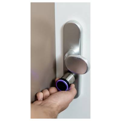 Hand unlocking a silver door with a cylindrical smart lock and lever handle.<br>