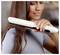 Woman straightening her long brown hair with a white flat iron, close-up beauty styling scene.