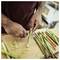 Person peeling asparagus spears with a vegetable peeler on a cutting board in a kitchen.<br>