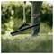 A person uses a rake-like garden tool to gather or level grass in a yard.<br>