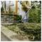 Person using a garden rake to clear leaves and debris from a yard near a house.
