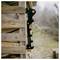 Black FISKARS firewood splitter attached to a stacked wood crate outdoors, with an orange button and blurred yard in the background.