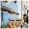 Person grates orange zest over a cutting board with appetizers and ingredients laid out, preparing food in a kitchen.