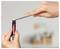 Hands use tweezers to insert a small object into the tip of a marker pen being held upright.