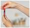 Hands holding a red-and-black marker pen upright against a blurred indoor background.