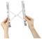 Hands holding a silver scissor-style expanding wall shelf bracket open against a white background.