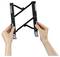 Hands hold an adjustable black scissor-style wall mount bracket with foldable arms on a white background.