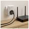 Wi-Fi router on a wooden shelf plugged into a wall outlet via a power adapter, with two antennas and visible status lights.