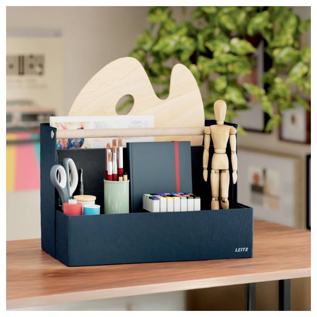 Desktop organizer with art supplies, scissors, pens, markers, and a wooden mannequin on a table with a palette in back.