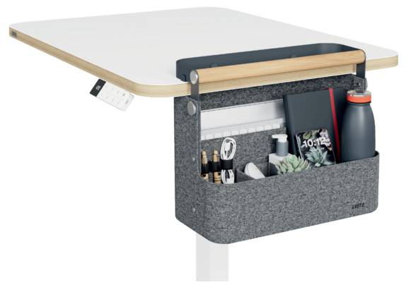 Under-desk hanging organizer with pockets holding pens, notebook, phone, sanitizer, and water bottle attached to a table edge.