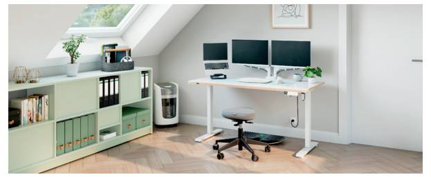 Modern home office with dual monitors on a white desk, swivel chair, shelving, printer, and skylight in a bright attic room.