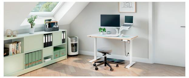 Minimal home office under a sloped ceiling with a white desk, dual monitors, swivel chair, storage cabinet, and bookshelves.
