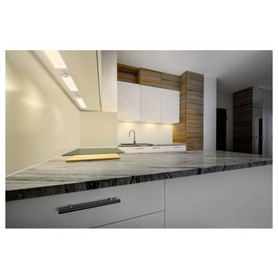 Modern kitchen interior with a marble island, white cabinets, wood accents, and a sink under under-cabinet lighting.