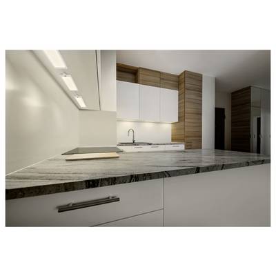 Modern kitchen interior with white cabinets, wood accents, built-in sink, and a large gray marble countertop in the foreground.