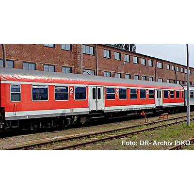 Red and white passenger train cars on railway tracks beside a brick building, with 'Foto: DR-Archiv PIKO' text in the corner.