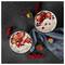 Two bowls of yogurt or oatmeal topped with strawberries, apple slices, and red currants on a dark surface with a blue cloth.