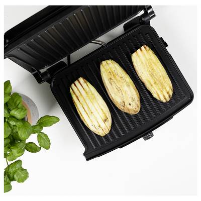 Open contact grill with three grilled zucchini slices and a potted basil plant on a white surface.