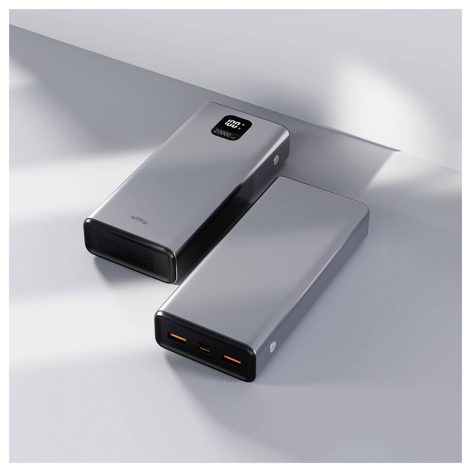 Two sleek gray portable power banks on a white surface, one showing a digital battery display and the other with illuminated USB ports.